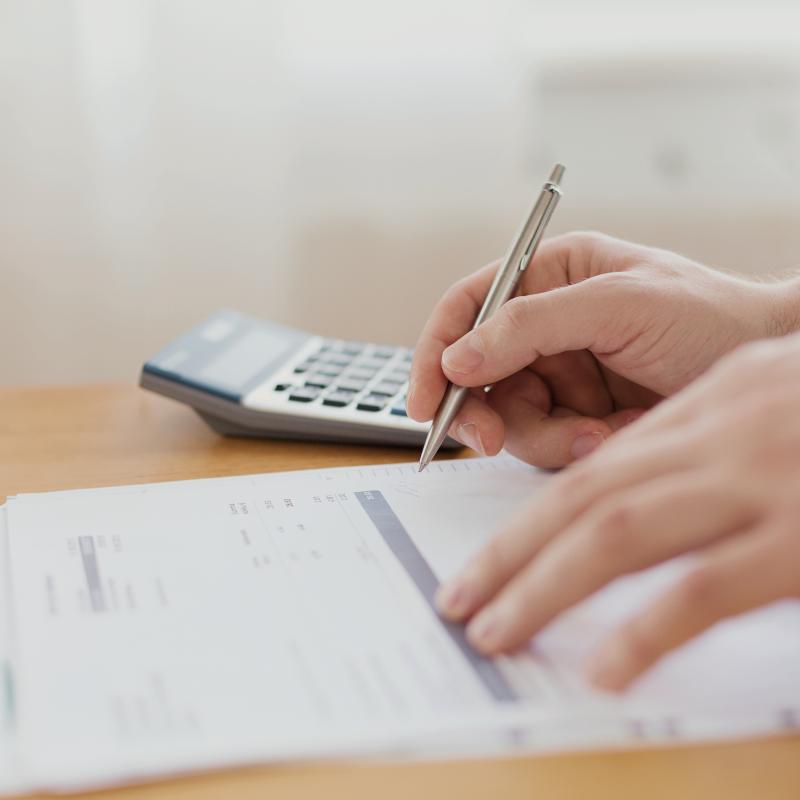 Hands doing paperwork next to a calculator