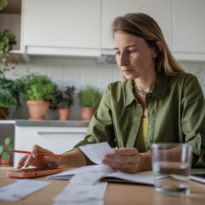 Person sitting at a desk with a laptop, looking at paperwork